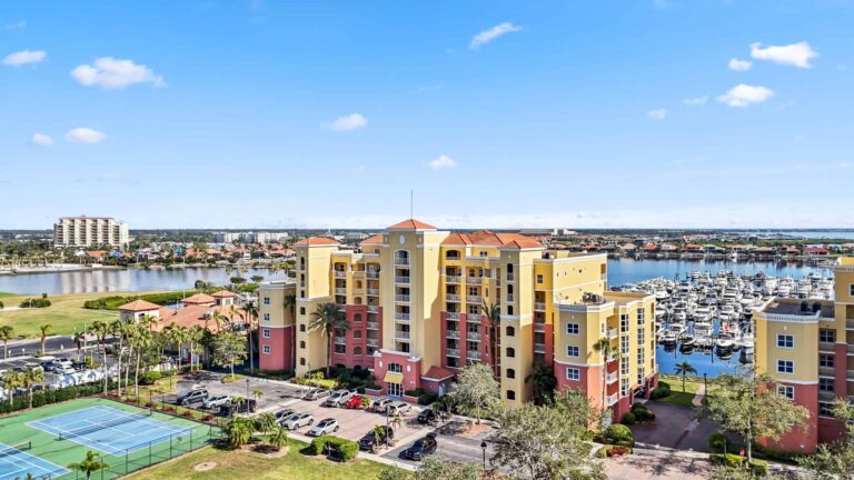 A sky view of 606 Riviera Dunes Way condo building, with view of the marina and tennis courts.